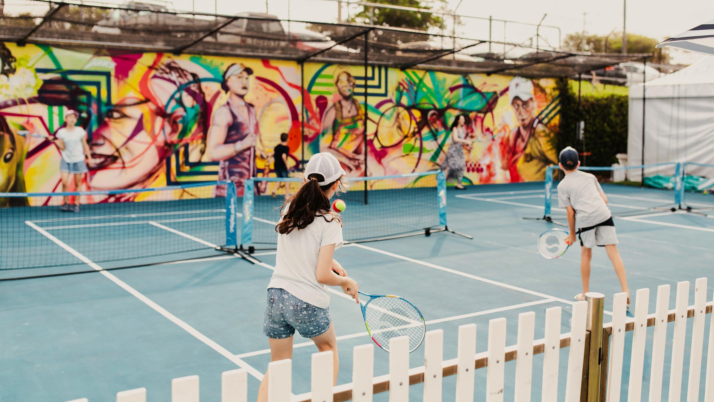 Four children playing tennis on a mini tennis court