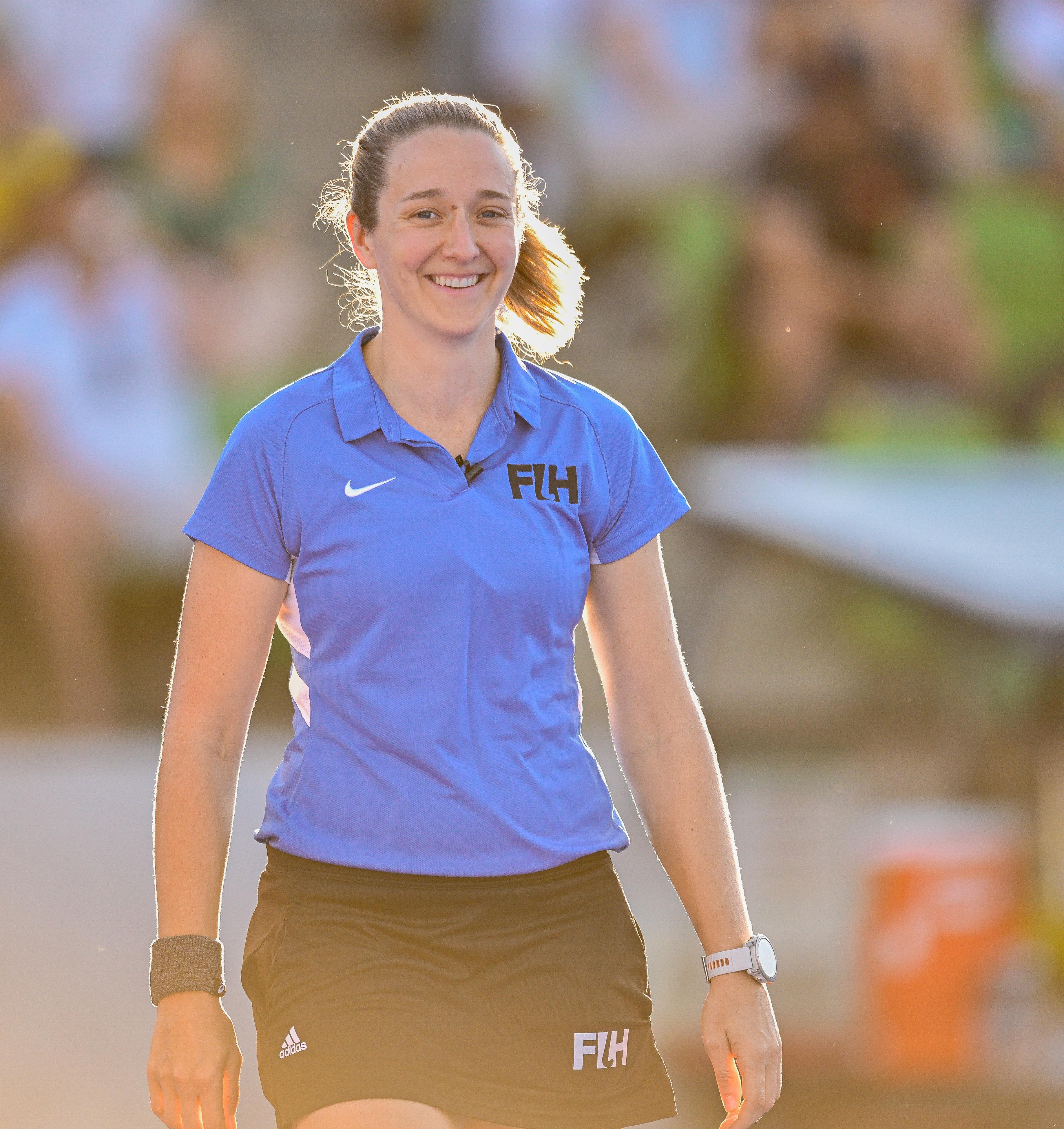 Aleisha Neumann is wearing a blue t-shirt and black skirt, smiling at the camera. 