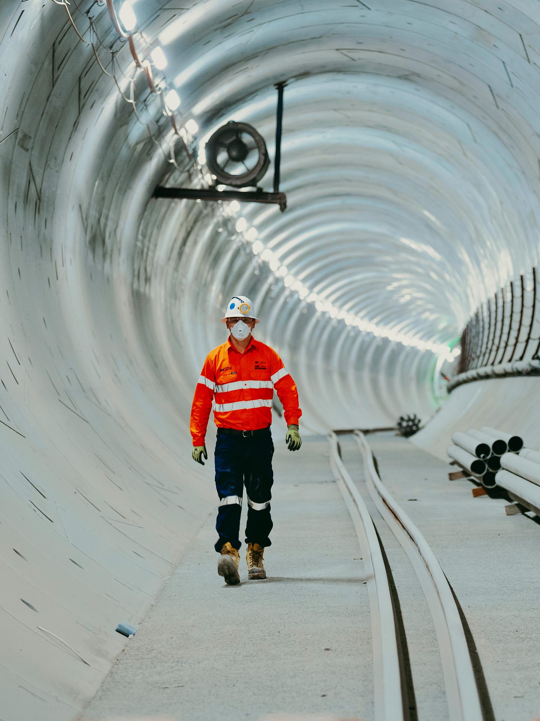 Worker in high vis and safety equipment walking through a tunnel thats in the process of being built
