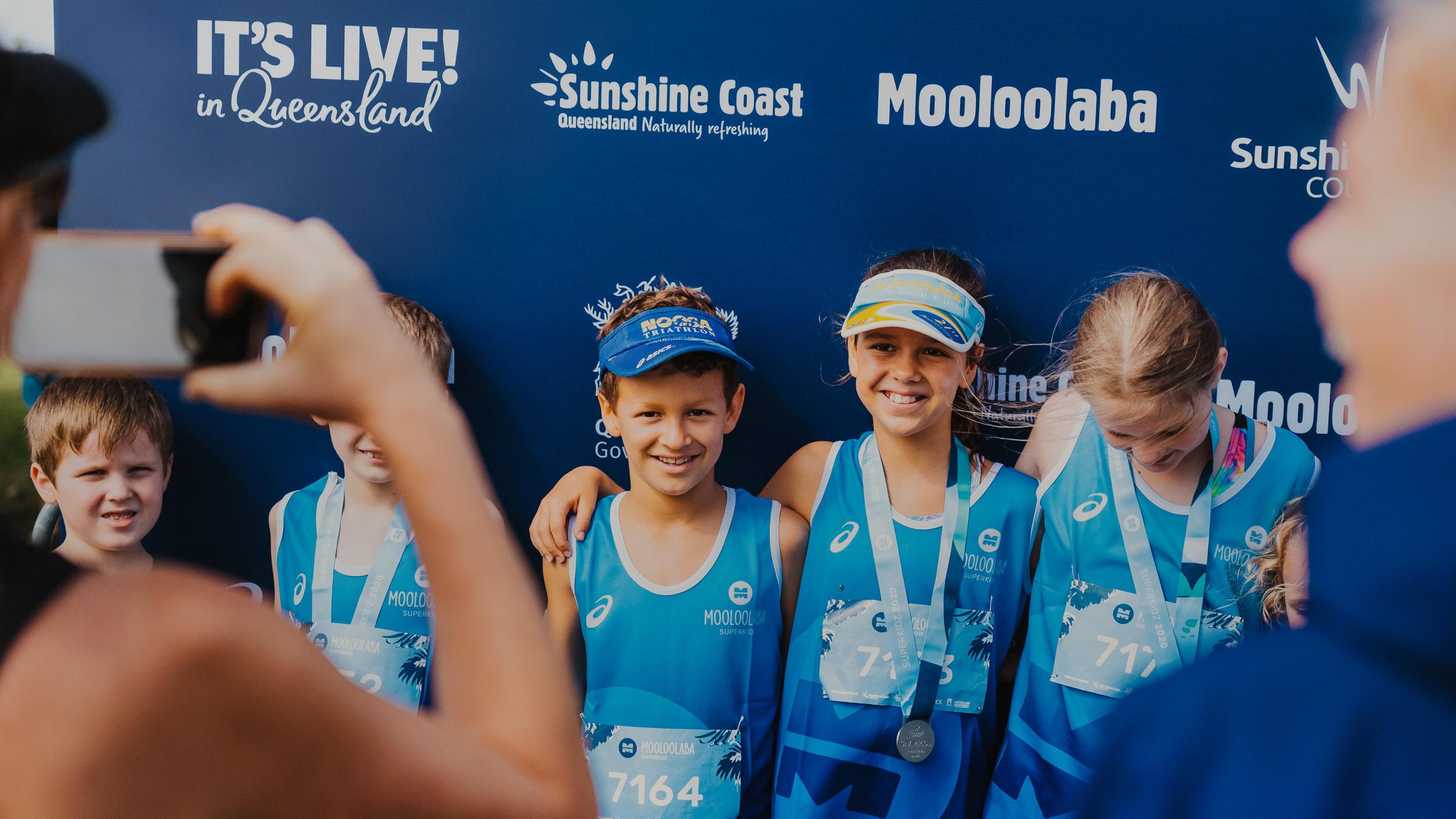 Parents taking pictures of young athletes who received medals in the Mooloolaba Triathlon