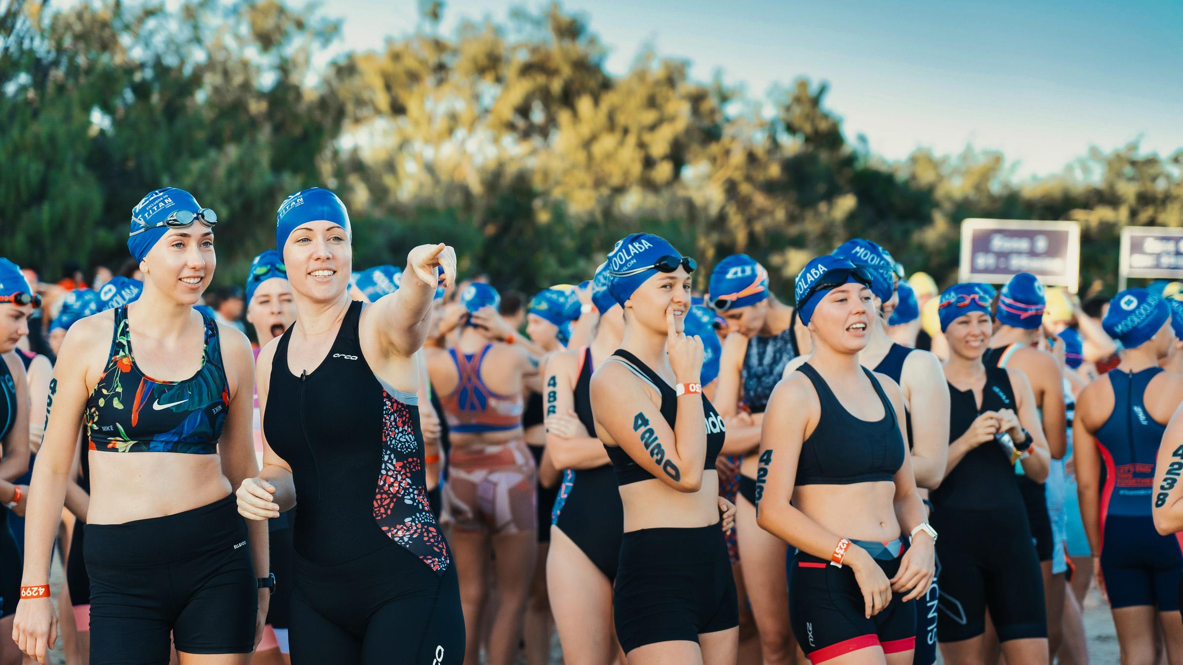 Crowd of swimmers wearing goggles and caps, standing together before a race