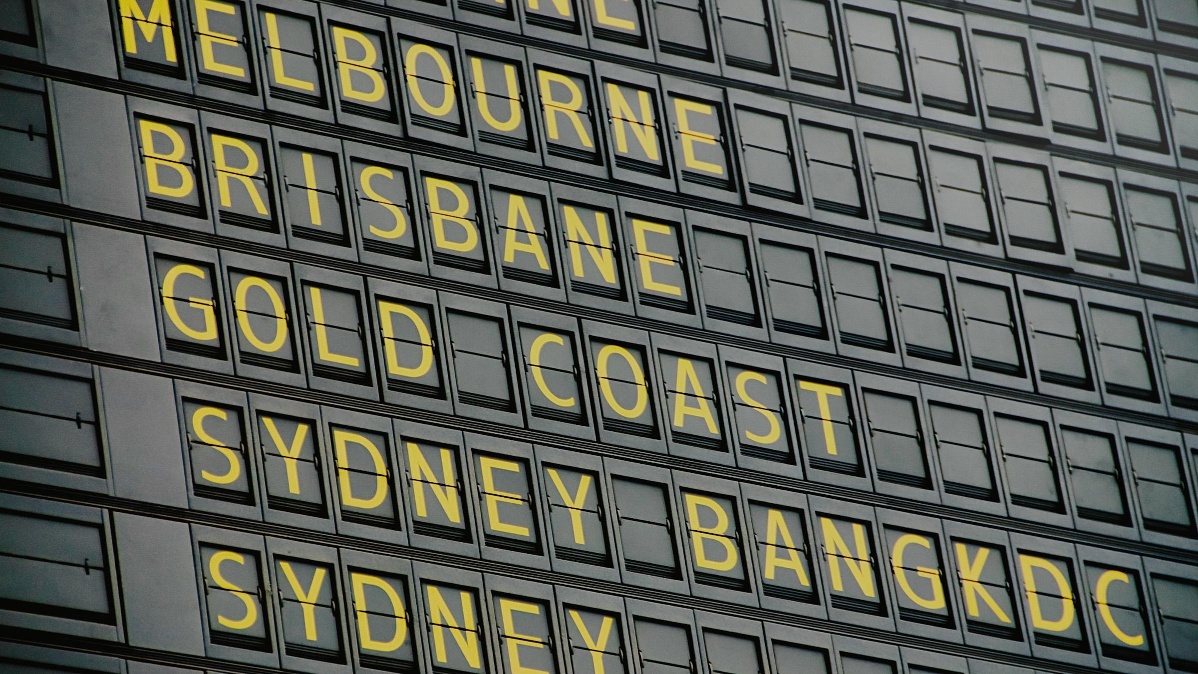 Black departure board showing Australian destinations with yellow letters
