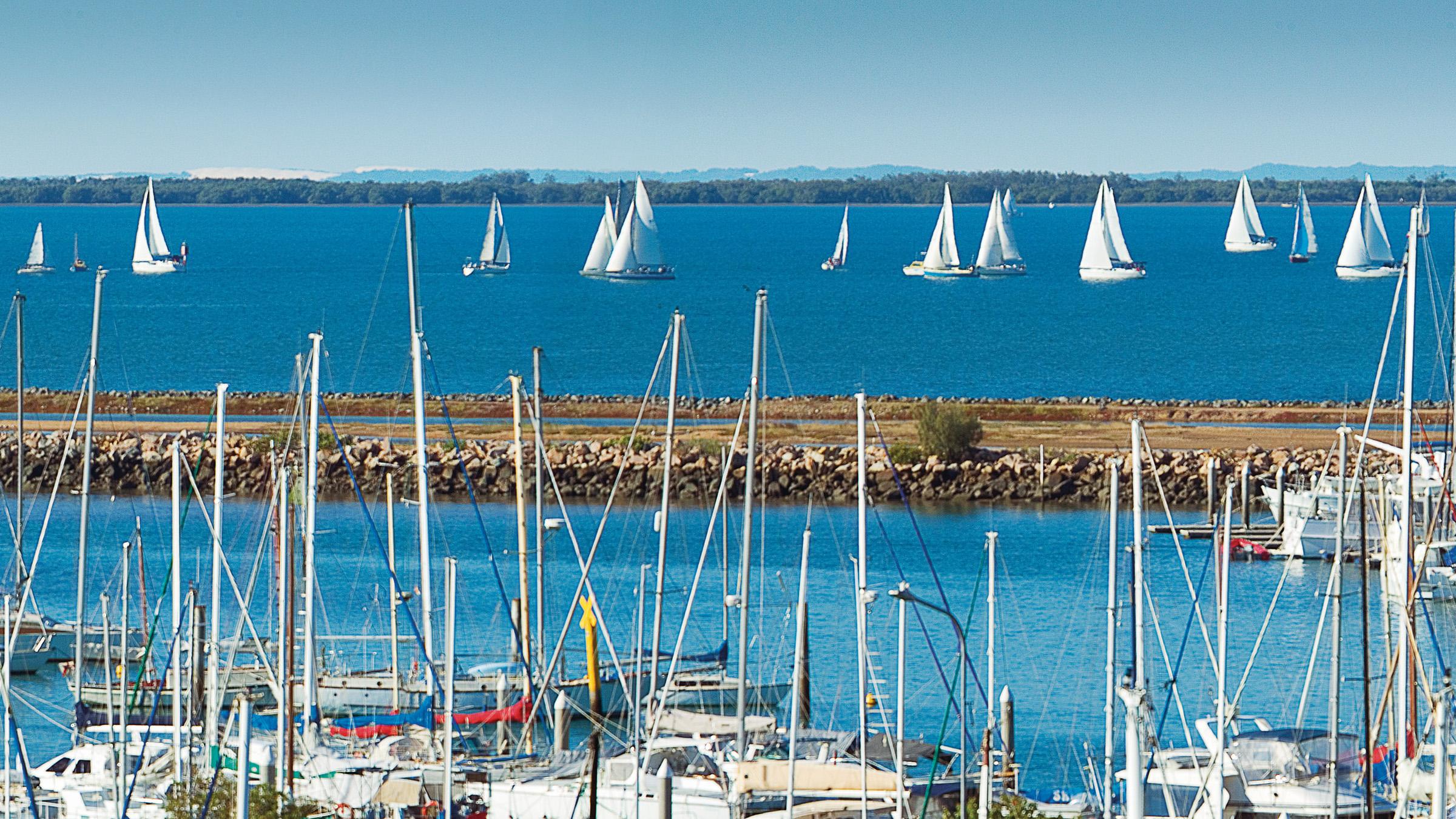 Sailboats out on the ocean and parked in a harbour on a bright blue day