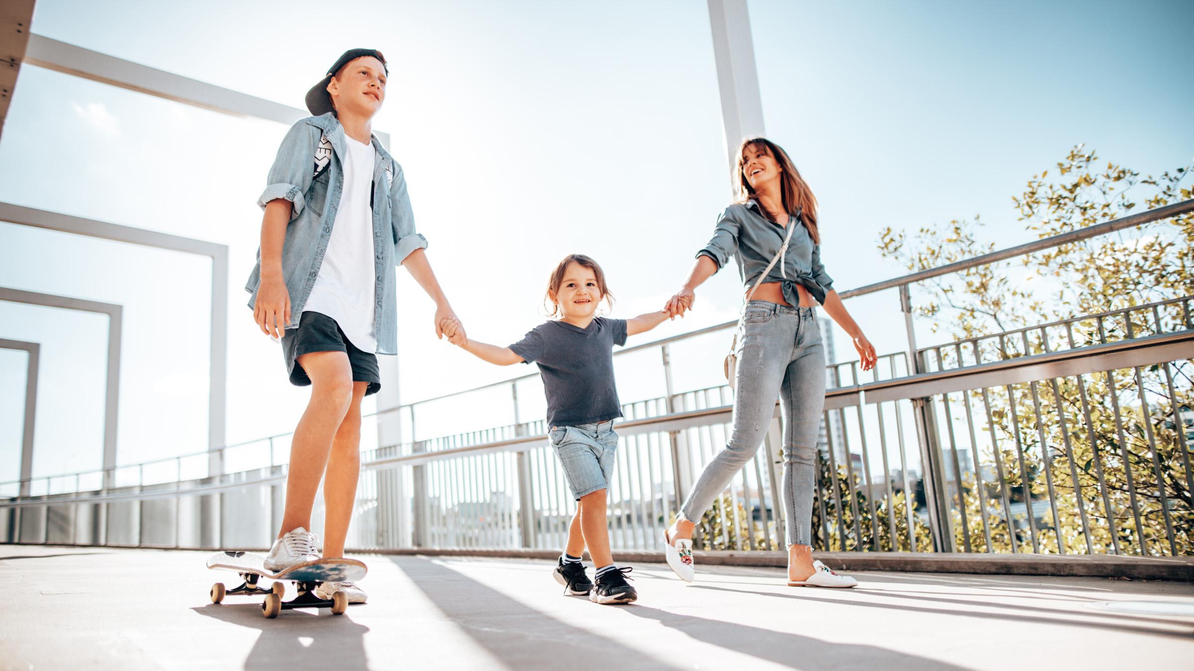 Mum and two children holding hands while walking across a bridge