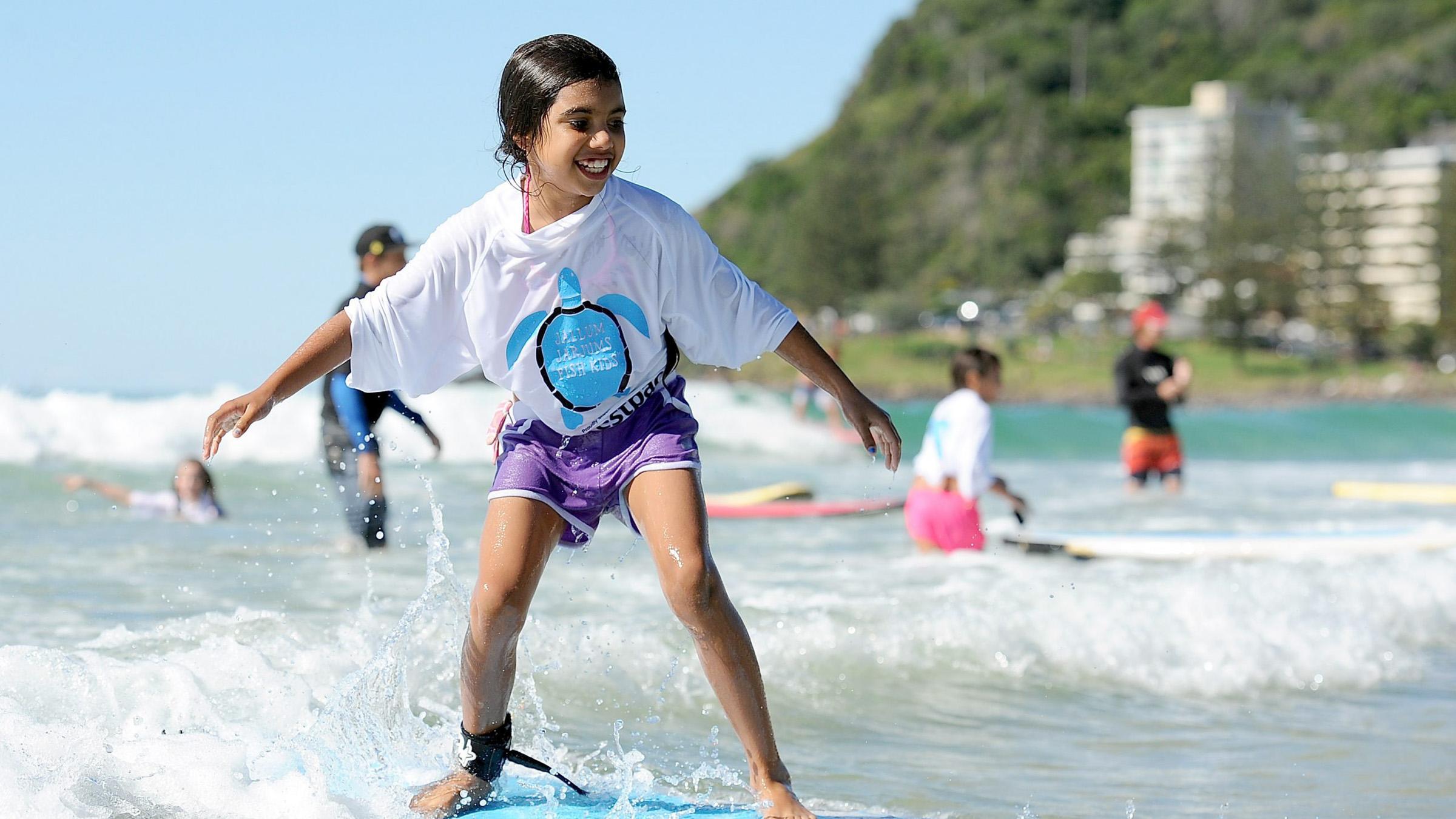 Young surfer standing upright on her board, riding the waves