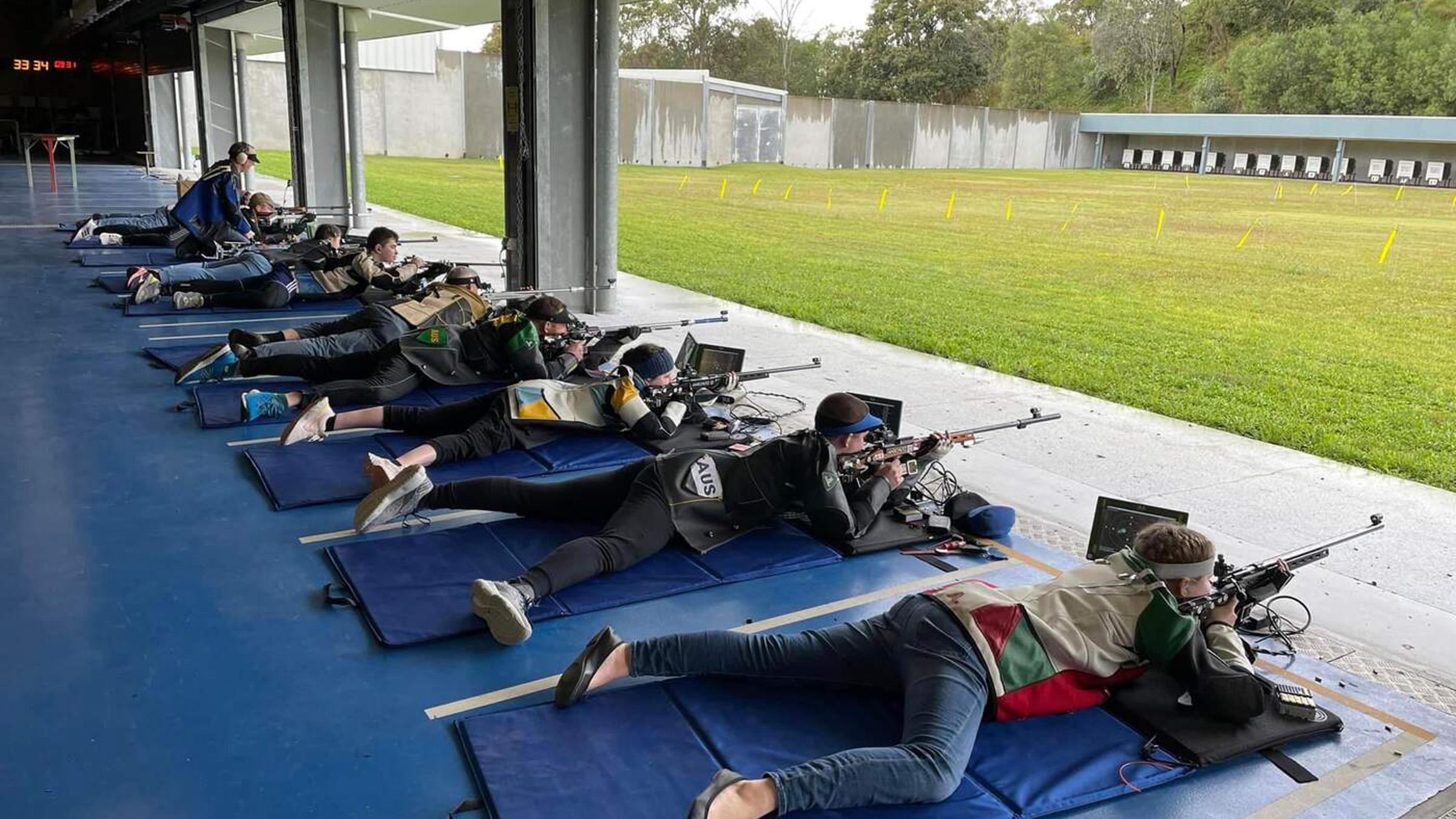 Group of athlete shooters laying in prone position, preparing to shoot their rifles within the Brisbane shooting centre