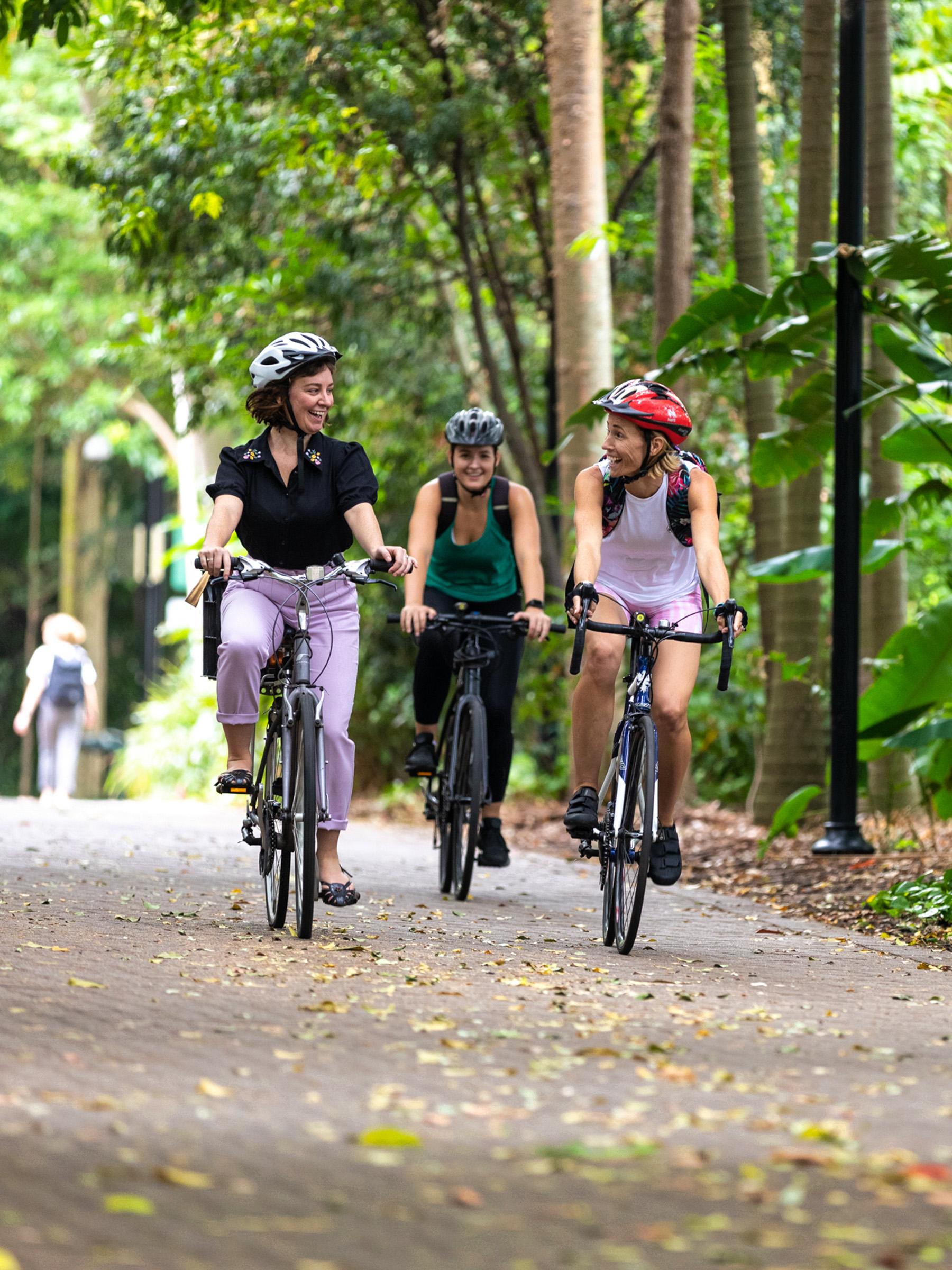 Three friends cycling together through the Brisbane Botanical Gardens