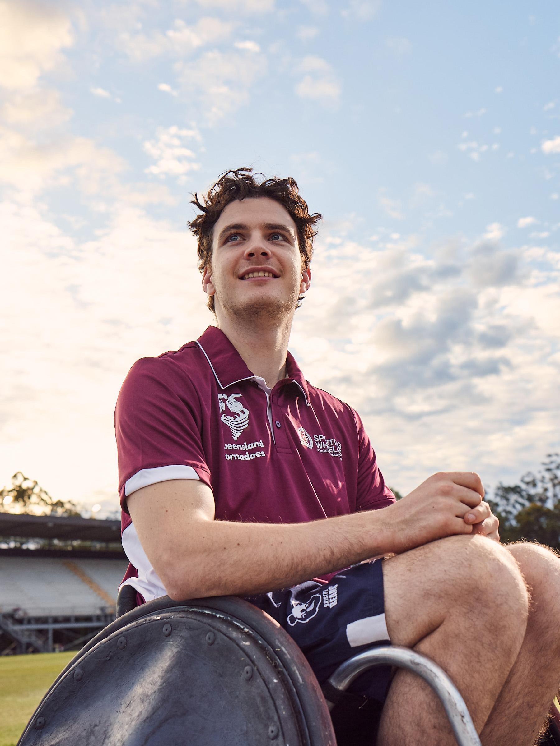 Low-angle shot of a smiling athlete in a wheelchair on a sports oval
