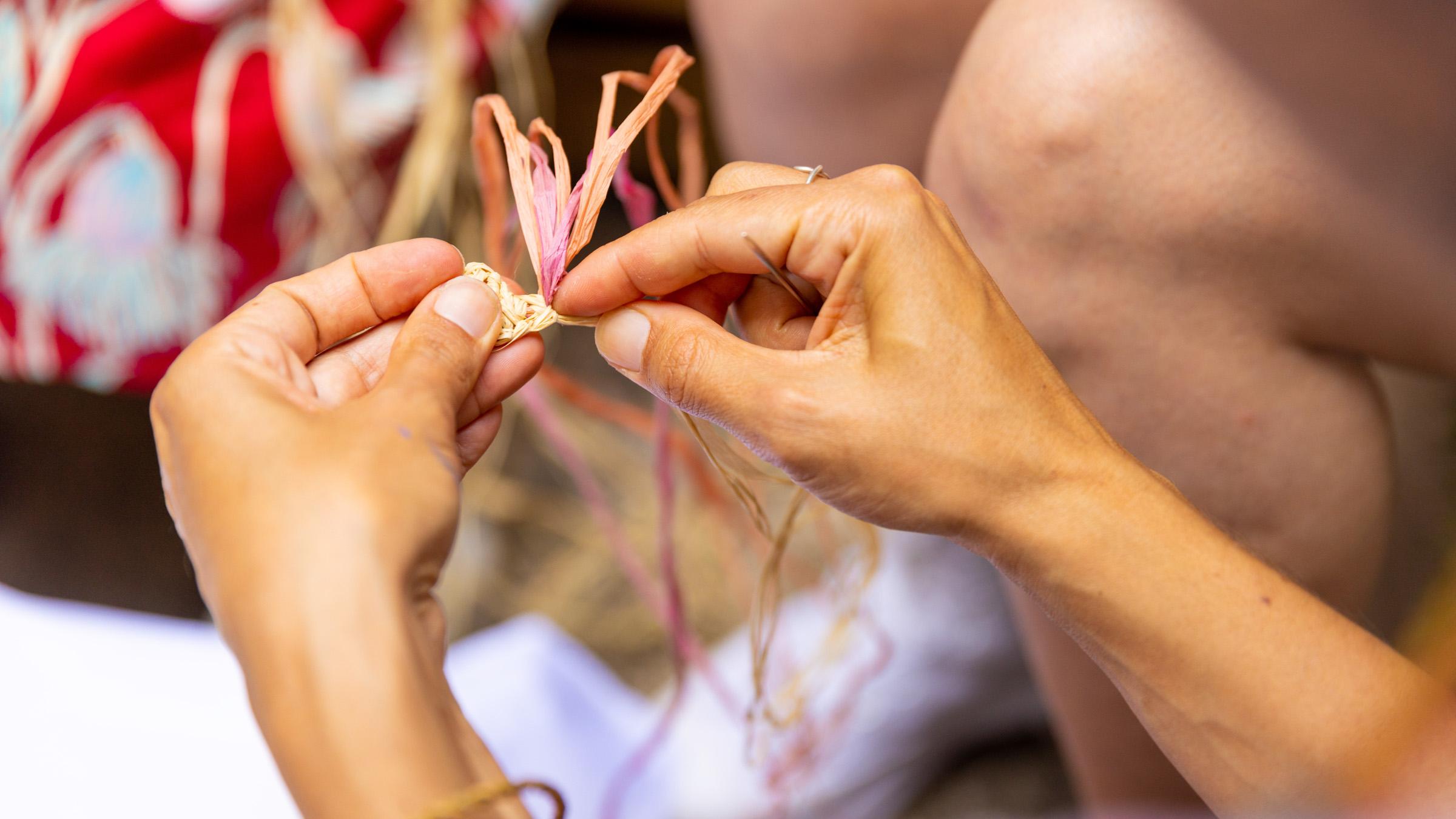 Close up of person's hands weaving natural strands together