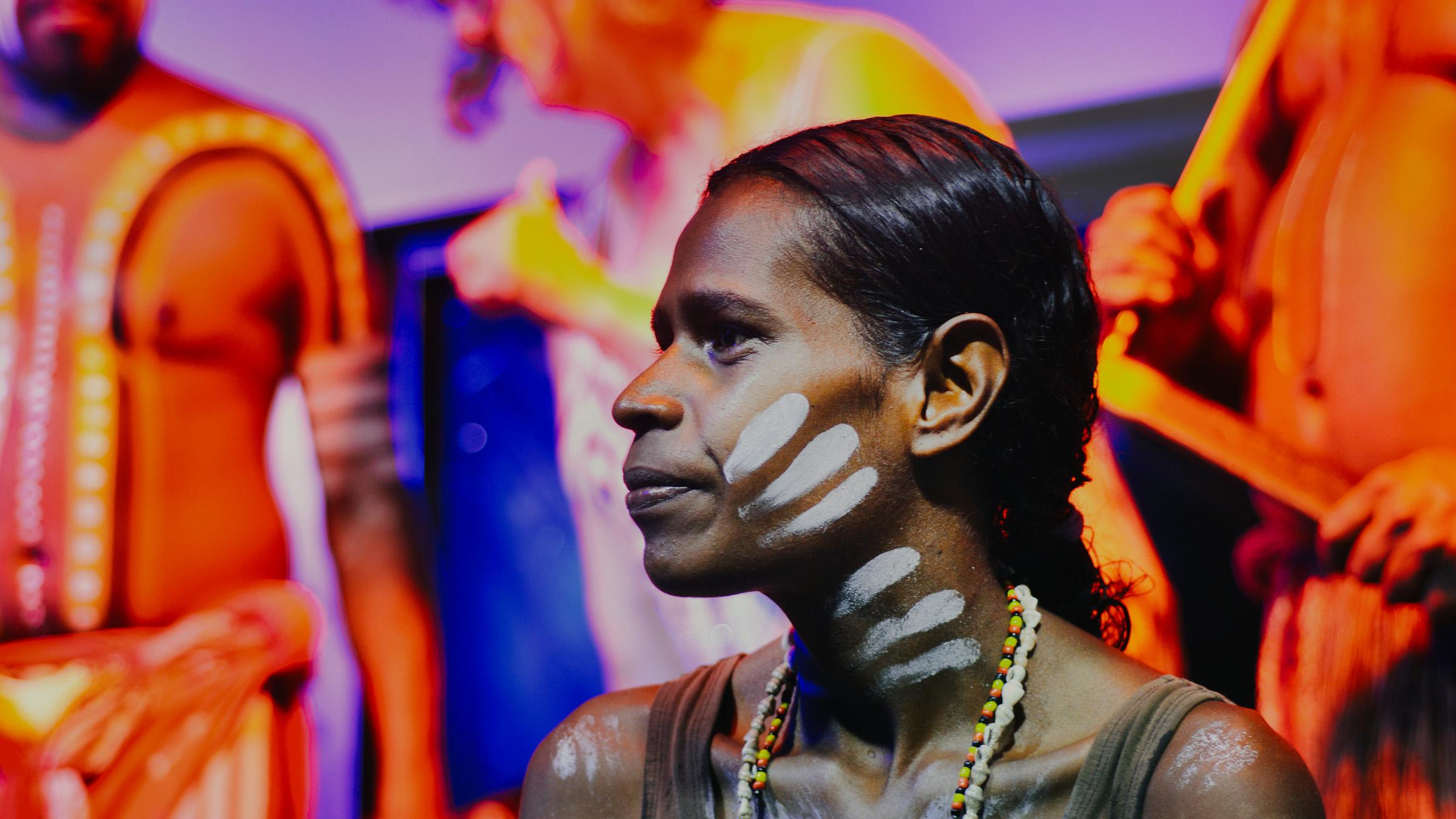Young First Nations woman with traditional face and body paint performing during a cultural show in Queensland, Australia.
